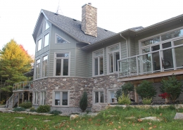 Residential project - green stone house with horizontal siding - rear view